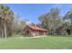 Charming home featuring a red metal roof and surrounded by mature trees and a lush green lawn at 255 Butterfly Forest Rd, Geneva, FL 32732