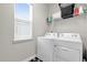Functional laundry room with a side-by-side washer and dryer, shelving, and a window for natural light at 2890 Avian Loop, Kissimmee, FL 34741