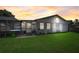 Backyard at sunset featuring a screened pool enclosure and green lawn at 290 Orange Ave, St Cloud, FL 34769