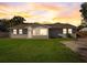 Charming single-story home with lush green lawn and beautiful sunset, providing an inviting curb appeal at 290 Orange Ave, St Cloud, FL 34769