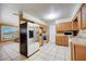 Open kitchen with stainless steel refrigerator, wood cabinets, and tile floors at 290 Orange Ave, St Cloud, FL 34769