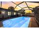A private screened-in pool with clear blue water and brick surround with a vivid sunset at 290 Orange Ave, St Cloud, FL 34769