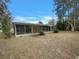 A screened lanai is attached to this cozy home under a bright blue sky with mature tree cover, enhancing the outdoor living space at 38 Emerald Ct, Ocala, FL 34472