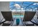 Lounge chairs on the paved pool deck near a shimmering pool with clear blue skies at 3811 Lana Ave, Davenport, FL 33897