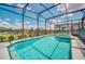 Beautiful screened-in pool with a blue-tiled spa and a glimpse of another pool behind at 3811 Lana Ave, Davenport, FL 33897