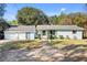Charming single-story home featuring an American flag, lush greenery and light blue paint at 530 Mckenzie Rd, Lake Helen, FL 32744