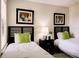 Bedroom featuring twin beds, matching artwork, neutral paint, and a bedside table with lamp at 8141 Roseville Blvd, Davenport, FL 33896