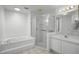 Bright bathroom features a tiled tub, separate glass enclosed shower, and a vanity with a large mirror at 600 Park Valley Cir, Minneola, FL 34715