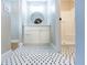 Bright bathroom boasts a modern white vanity, round mirror, hexagon tile floor, and a glass-enclosed shower at 10142 Richardson Ct, Orlando, FL 32825