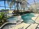 Screened pool and spa overlooking pond surrounded by beautiful landscaping at 10446 Stone Glen Dr, Orlando, FL 32825