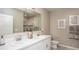 Well-lit bathroom with double sinks, a large mirror, and a tiled shower at 2293 Pecos Ct, Kissimmee, FL 34759