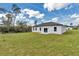 A view of the backyard with well-maintained lawn and white house with sliding glass door and an outdoor patio at 2844 Sw 162Nd Street Rd, Ocala, FL 34473