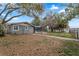 View of the home's gray exterior, a screened-in patio and lush grounds with mature trees at 37224 Apiary Rd, Grand Island, FL 32735