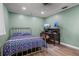 This bedroom is light green with a traditional bed, desk, and wood floors at 37224 Apiary Rd, Grand Island, FL 32735