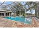 Enclosed pool area with stone patio, built in waterfall feature and screened enclosure for pest control at 37224 Apiary Rd, Grand Island, FL 32735