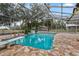 Enclosed pool area with stone patio, diving board, waterfall feature, and screened enclosure at 37224 Apiary Rd, Grand Island, FL 32735