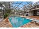 Enclosed pool area with stone patio, diving board, waterfall feature, and screened enclosure at 37224 Apiary Rd, Grand Island, FL 32735