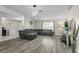 Bright living room featuring gray laminate floors, a sectional couch, and contemporary light fixture at 4100 Cannon Ct, Kissimmee, FL 34746