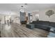 Open concept living room with wood-look flooring and a gray sectional sofa, flowing seamlessly into the dining area and kitchen at 4100 Cannon Ct, Kissimmee, FL 34746