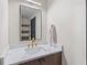 Modern bathroom featuring sleek vanity with white countertop and brushed gold fixtures, plus black framed mirror and wooden shelf at 5447 Brookline Dr, Orlando, FL 32819