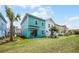 View of the back of a colorful home with a patio and a large lawn at 8179 Coconut Pl, Kissimmee, FL 34747