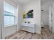 Bright hallway with wood-look tile floors features a decorative console table and a view into a bedroom with large windows at 8179 Coconut Pl, Kissimmee, FL 34747