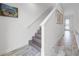 Bright hallway with wood-look tile floors leading to a staircase and the front door, adorned with beach-themed artwork at 8179 Coconut Pl, Kissimmee, FL 34747