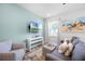 Cozy living room features a plush gray sofa, armchair, striped ottoman, and a mounted TV, creating a relaxing atmosphere at 8179 Coconut Pl, Kissimmee, FL 34747