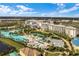 Aerial view of a luxurious pool with palm trees, blue umbrellas, lounge chairs and adjacent buildings at 8179 Coconut Pl, Kissimmee, FL 34747