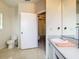 Bathroom with toilet and sink vanity with an open doorway to an adjacent carpeted room at 114 Vista Verdi Cir # 328, Lake Mary, FL 32746