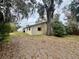 View of the back of the home with mature trees in a spacious yard at 115 S Lake Pleasant Rd, Apopka, FL 32703