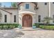 Elegant arched double doors with a canvas awning and lush landscaping create a grand entrance at 135 James Pl, Maitland, FL 32751