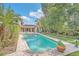 The private backyard pool and patio feature tropical landscaping, lush green lawn, and beautiful stone pavers at 135 James Pl, Maitland, FL 32751