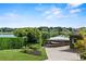 View of a paved driveway with a boat parked, lush landscaping, and lakeside homes in the background at 17201 Magnolia Island Blvd, Clermont, FL 34711