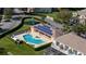 Aerial view of community pool with solar panels on clubhouse, playground, green grass, and mature trees at 17403 Placidity Ave, Clermont, FL 34714