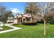 Landscaped front yard with lush green grass, palm trees, and colorful shrubbery at 1938 Filly Trl, Oviedo, FL 32765