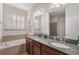 Double vanity bathroom with granite countertops, a soaking tub and a window with plantation shutters at 1947 Plantation Oak Dr, Orlando, FL 32824