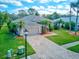 Inviting single-story home featuring a paver driveway, two-car garage, and lush landscaping with palm trees at 2439 Teton Stone Run, Orlando, FL 32828
