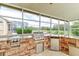 Outdoor kitchen under covered patio with stainless steel grill and refrigerator overlooks a lush golf course at 2439 Teton Stone Run, Orlando, FL 32828
