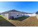 The house's backyard features a grassy lawn, a white fence, and a concrete retaining wall at 2447 Matterhorn Trl, Davenport, FL 33837