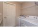 This laundry room features a side-by-side washer and dryer, wire rack shelving, and a white door at 2447 Matterhorn Trl, Davenport, FL 33837