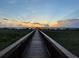 Inviting wooden walkway leads to a tranquil gazebo and stunning sunset over the lake at 2682 Mead Ave, St Cloud, FL 34771