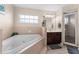Bright bathroom featuring a large soaking tub, walk-in shower, and vanity with dark wood cabinets at 302 Vista Loop, Davenport, FL 33897