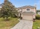 Front exterior of home featuring lush landscaping, a paver driveway, and a two-car garage at 302 Vista Loop, Davenport, FL 33897