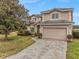 Exterior elevation of a two-story home with manicured landscaping and a paver driveway at 302 Vista Loop, Davenport, FL 33897