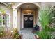 Charming front entrance featuring double doors, decorative wreaths, and lush landscaping at 302 Vista Loop, Davenport, FL 33897