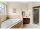 Bright bathroom features a soaking tub with tiled surround, dual vanity, and a glass shower enclosure at 302 Vista Loop, Davenport, FL 33897