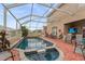 Outdoor pool area featuring a brick patio, a spa, a screened enclosure, and comfortable seating at 302 Vista Loop, Davenport, FL 33897