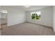 A carpeted bedroom with a window showing a treed view and an attached bathroom at 3349 Vesara Dr, Davenport, FL 33837