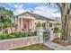 Charming pink home featuring a gated entryway, manicured landscaping, and a classic architectural design with white columns at 335 Beloit Ave, Winter Park, FL 32789